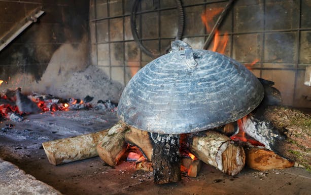 Traditional Croatian peka cooking over open fire on Dubrovnik food tour.