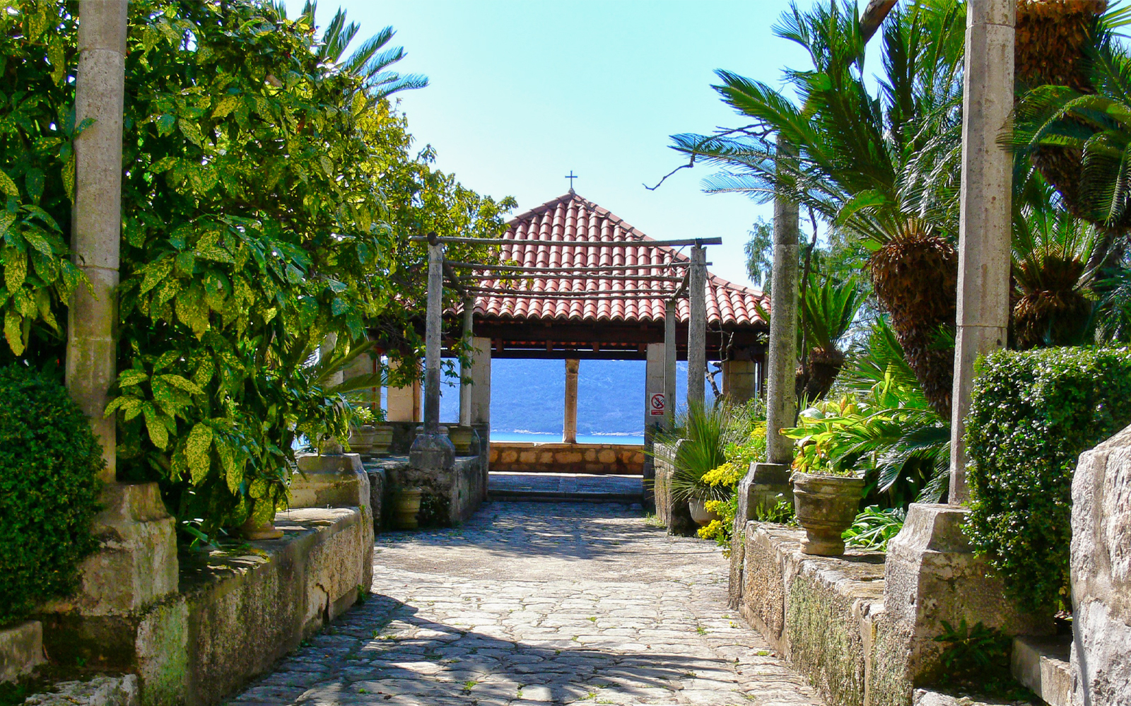 Stone pathway leading to a pavilion with a tiled roof, surrounded by lush greenery, on the Game of Thrones Driving Tour.