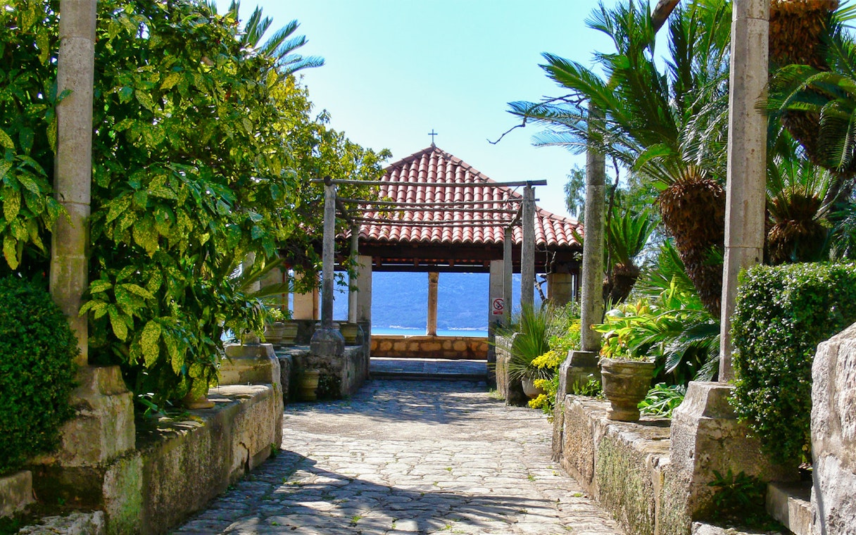 Stone pathway leading to a pavilion with a tiled roof, surrounded by lush greenery, on the Game of Thrones Driving Tour.