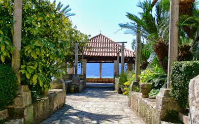 Stone pathway leading to a pavilion with a tiled roof, surrounded by lush greenery, on the Game of Thrones Driving Tour.