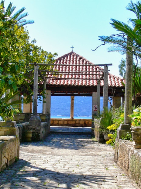 Stone pathway leading to a pavilion with a tiled roof, surrounded by lush greenery, on the Game of Thrones Driving Tour.