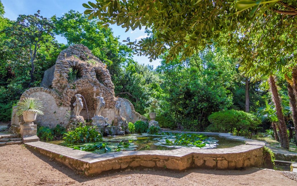 Stone grotto with statues and pond in lush garden, Game of Thrones driving tour location.