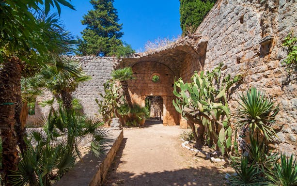 Stone archway and lush greenery on Game of Thrones boat tour in Dubrovnik, Croatia.