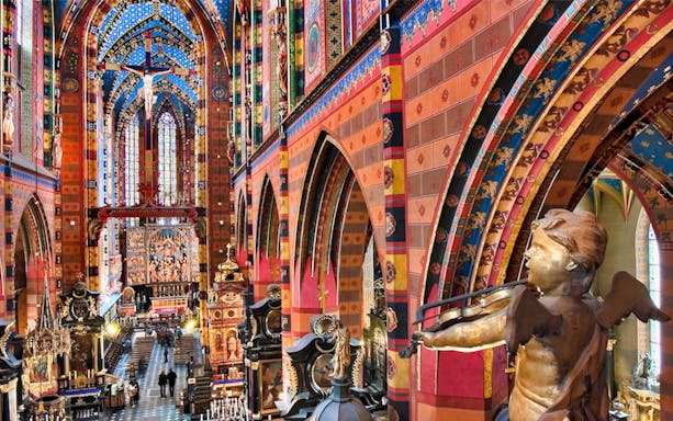 Interior of St. Mary’s Basilica in Krakow with colorful arches and a violin-playing angel statue.