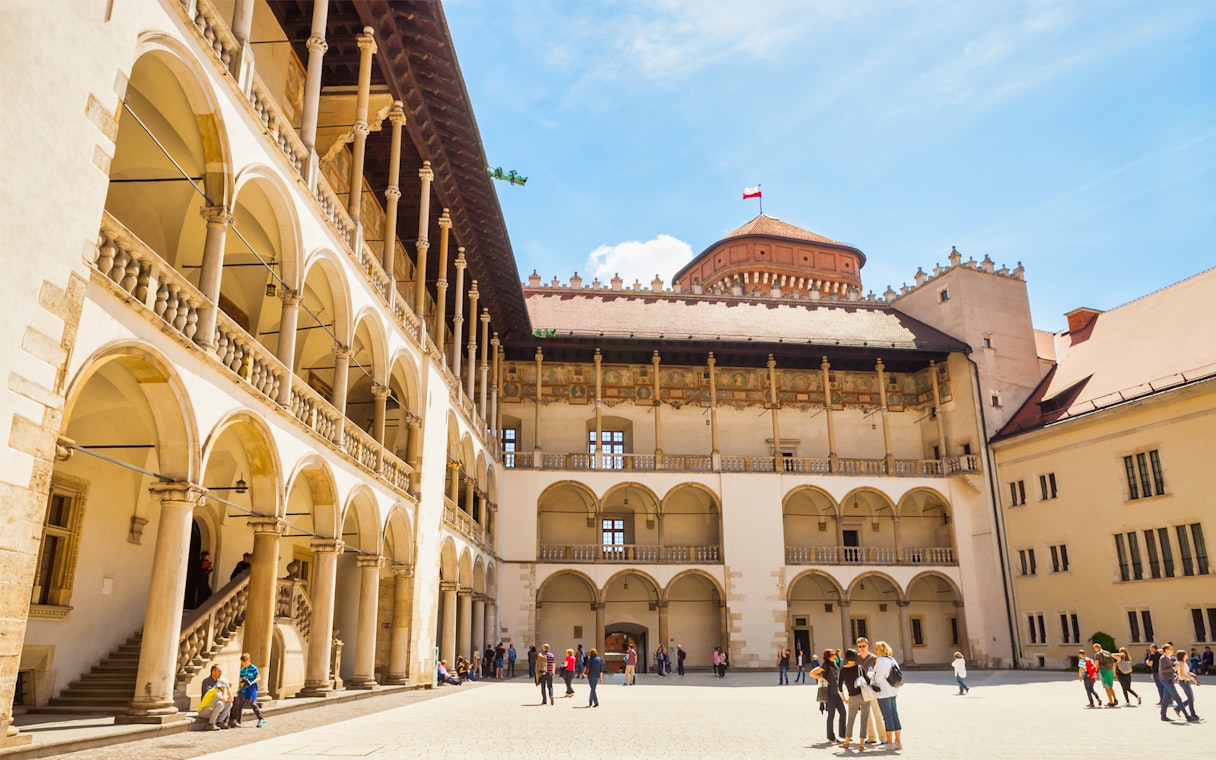 Wawel Royal Castle courtyard with tourists on a guided tour in Krakow, Poland.