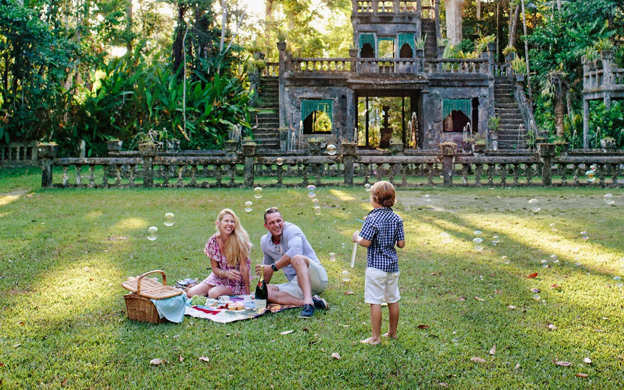 Family enjoying a picnic at Paronella Park with historic castle in the background.