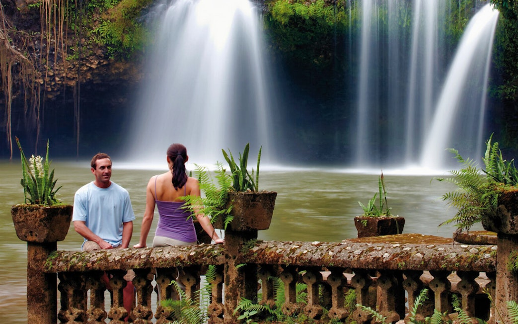 Couple sitting by a waterfall at Paronella Park, Australia.
