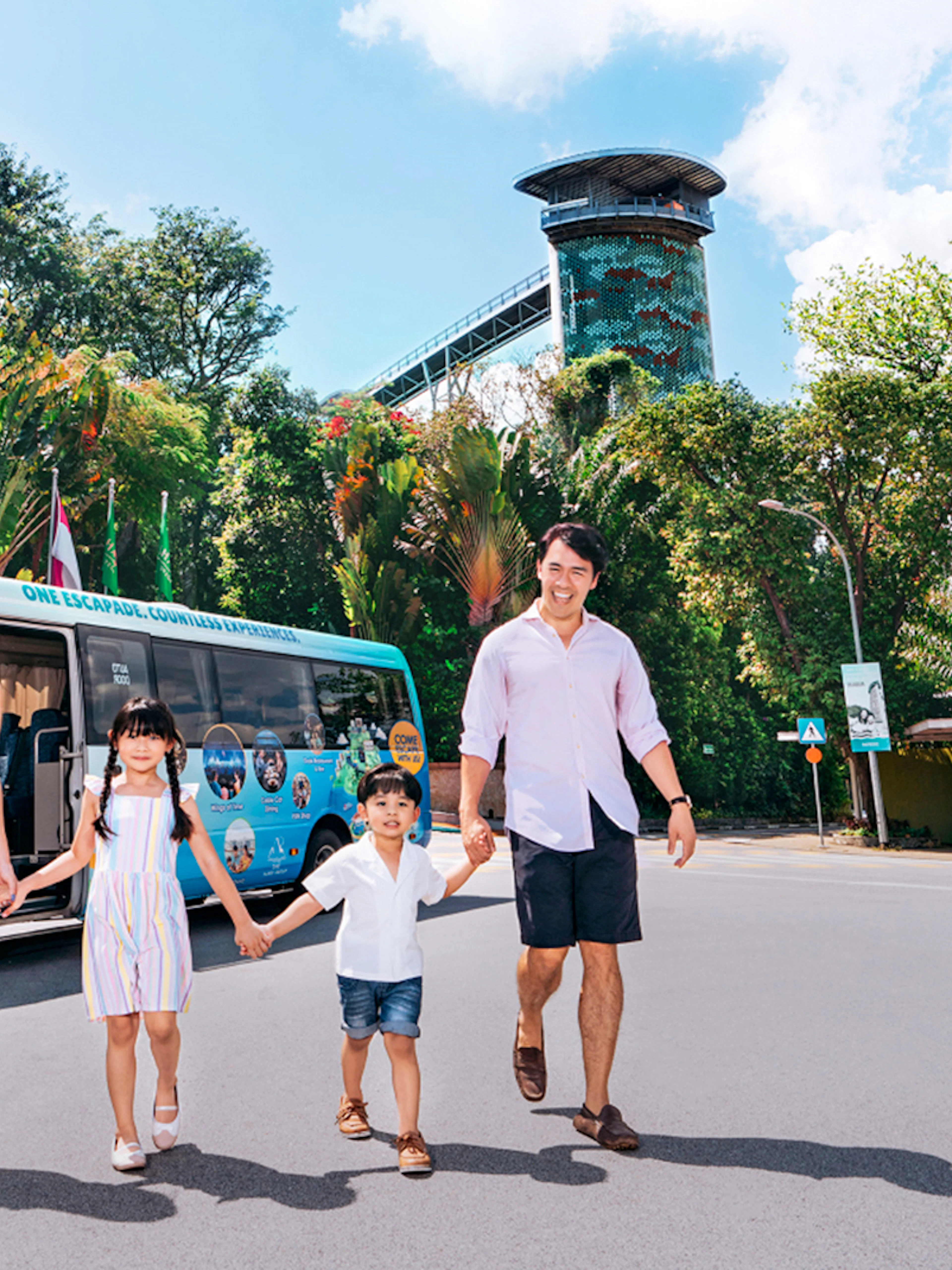 Family walking in front of a colorful tour bus on Sentosa Island.