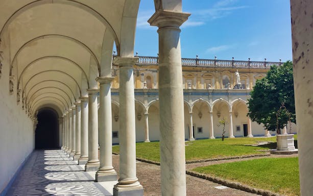Arched colonnade at Certosa e Museo di San Martino, Naples, with courtyard view.
