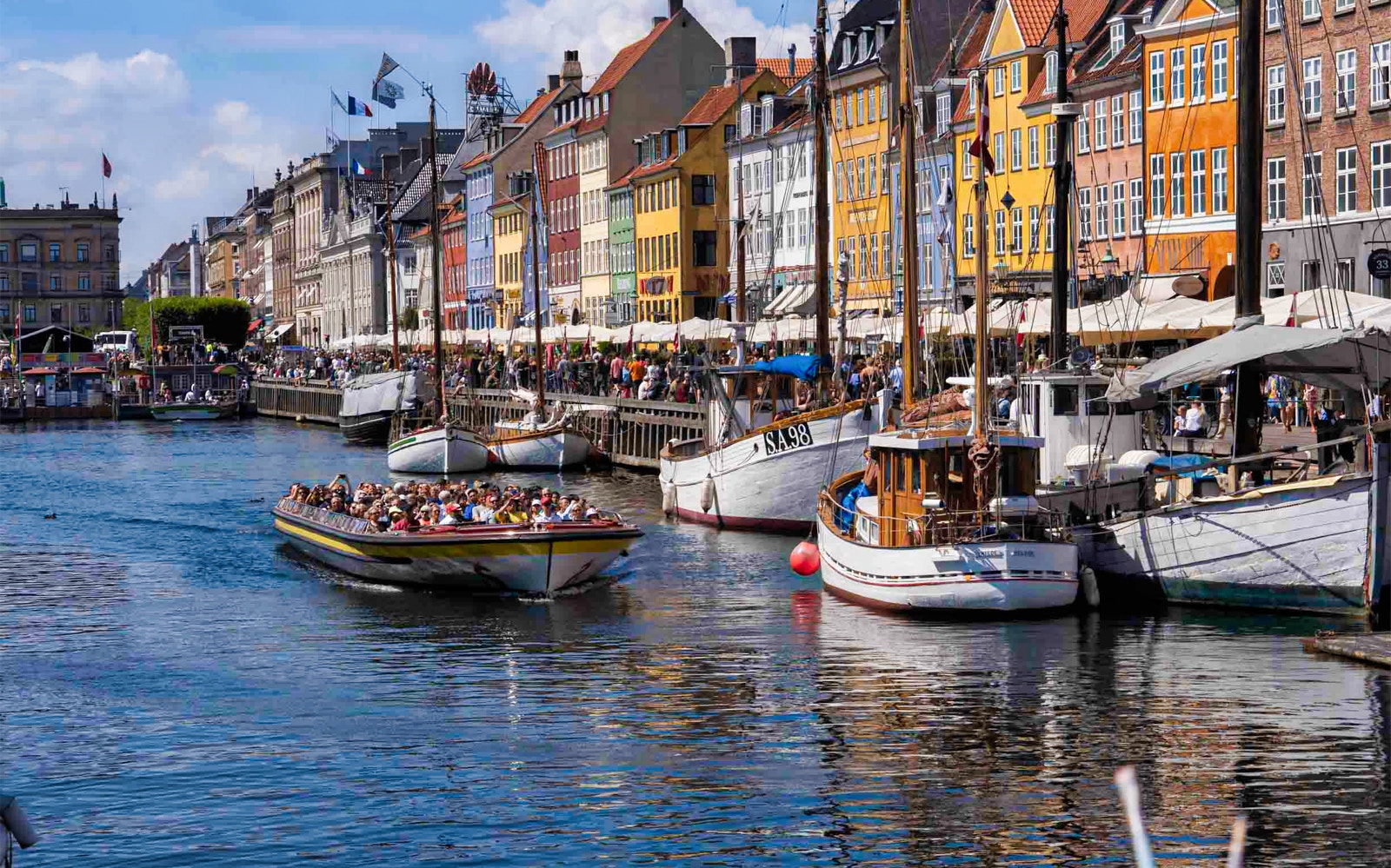 Boat tour on Copenhagen's canals passing colorful Nyhavn buildings, part of The Grand Tour from Ved Stranden.