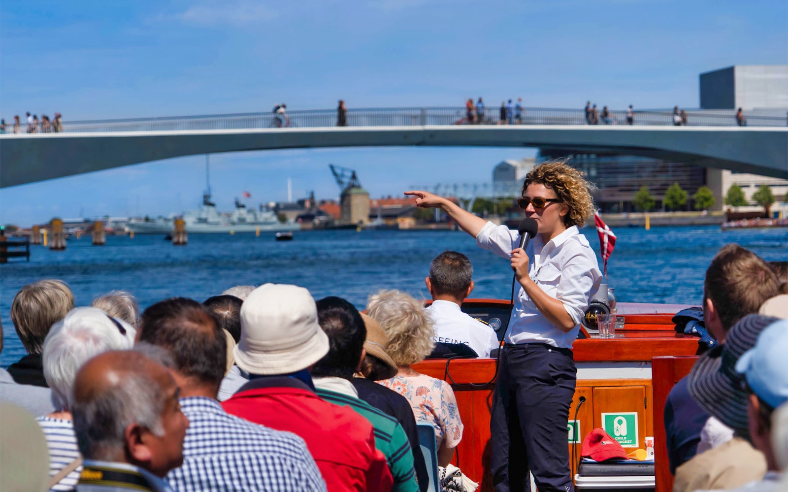Copenhagen canal boat tour passing colorful Nyhavn buildings.