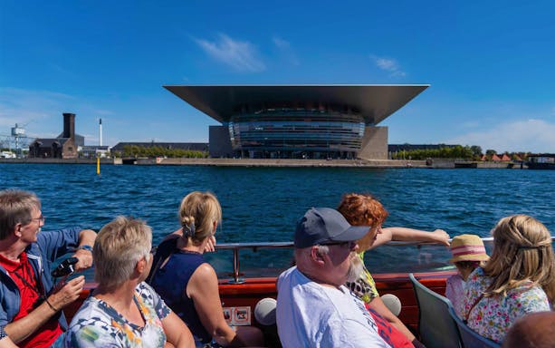 Tourists on a boat viewing the Copenhagen Opera House from Ved Stranden.