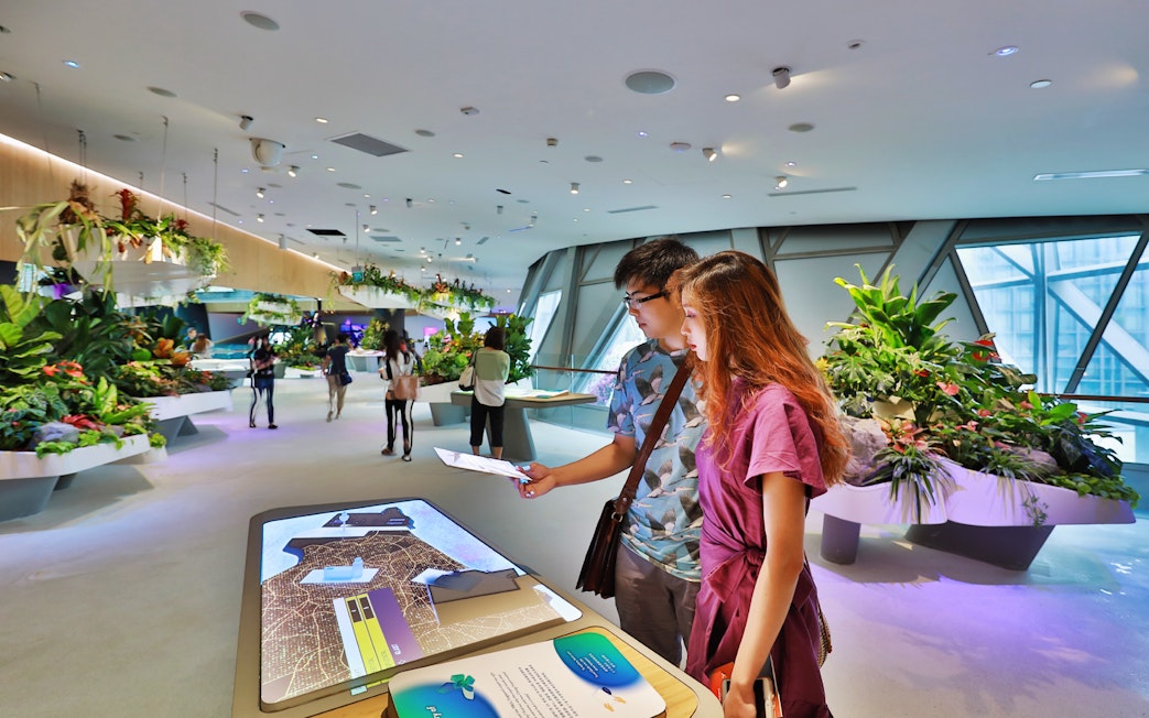 Visitors interacting with digital displays at Changi Experience Studio, surrounded by lush greenery.