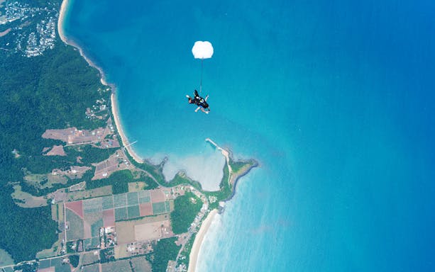 Skydiver descending over Mission Beach coastline from 15,000 feet.