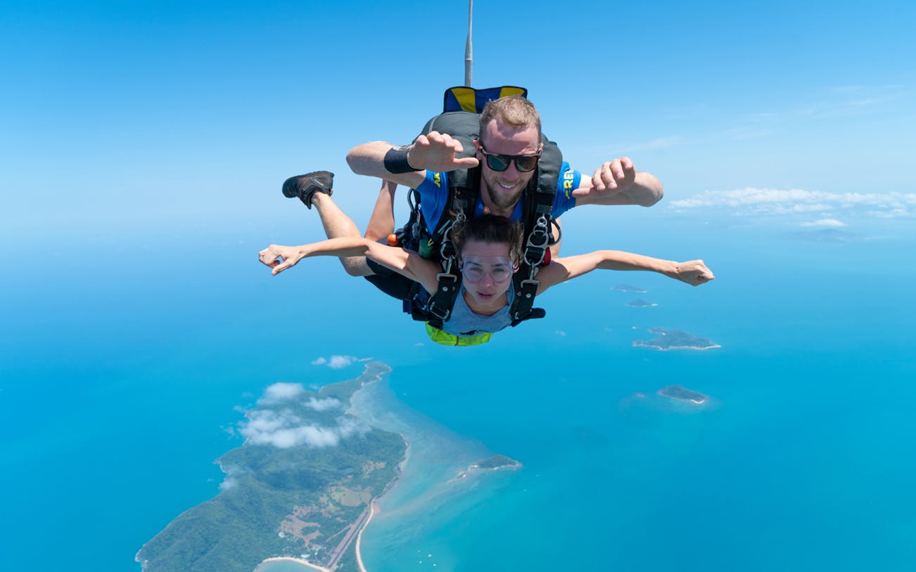 Tandem skydive over Mission Beach with ocean and islands below.