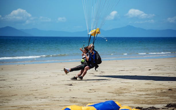 Tandem skydive landing on Mission Beach with ocean backdrop.