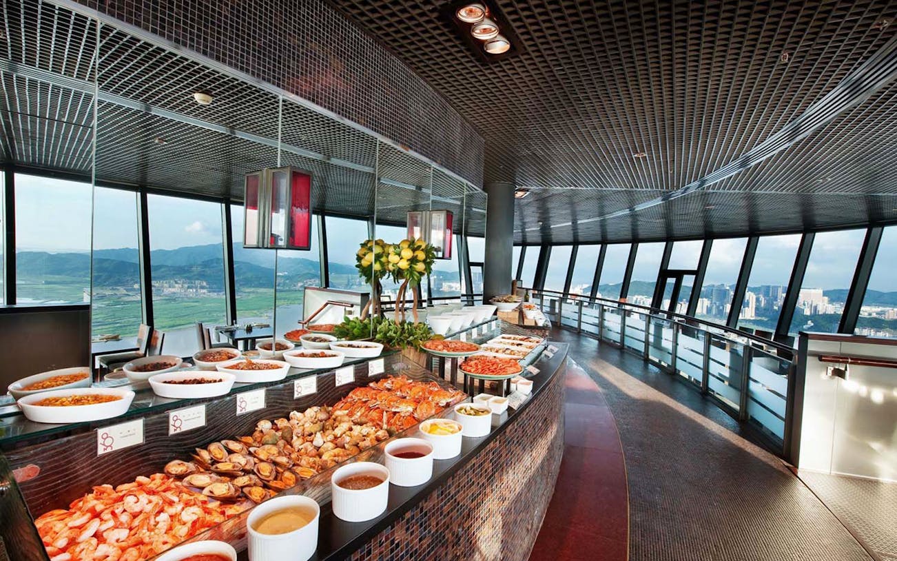 Buffet spread at 360 Cafe in Macau Tower with city view through large windows.