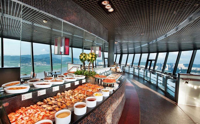 Buffet spread at 360 Cafe in Macau Tower with city view through large windows.