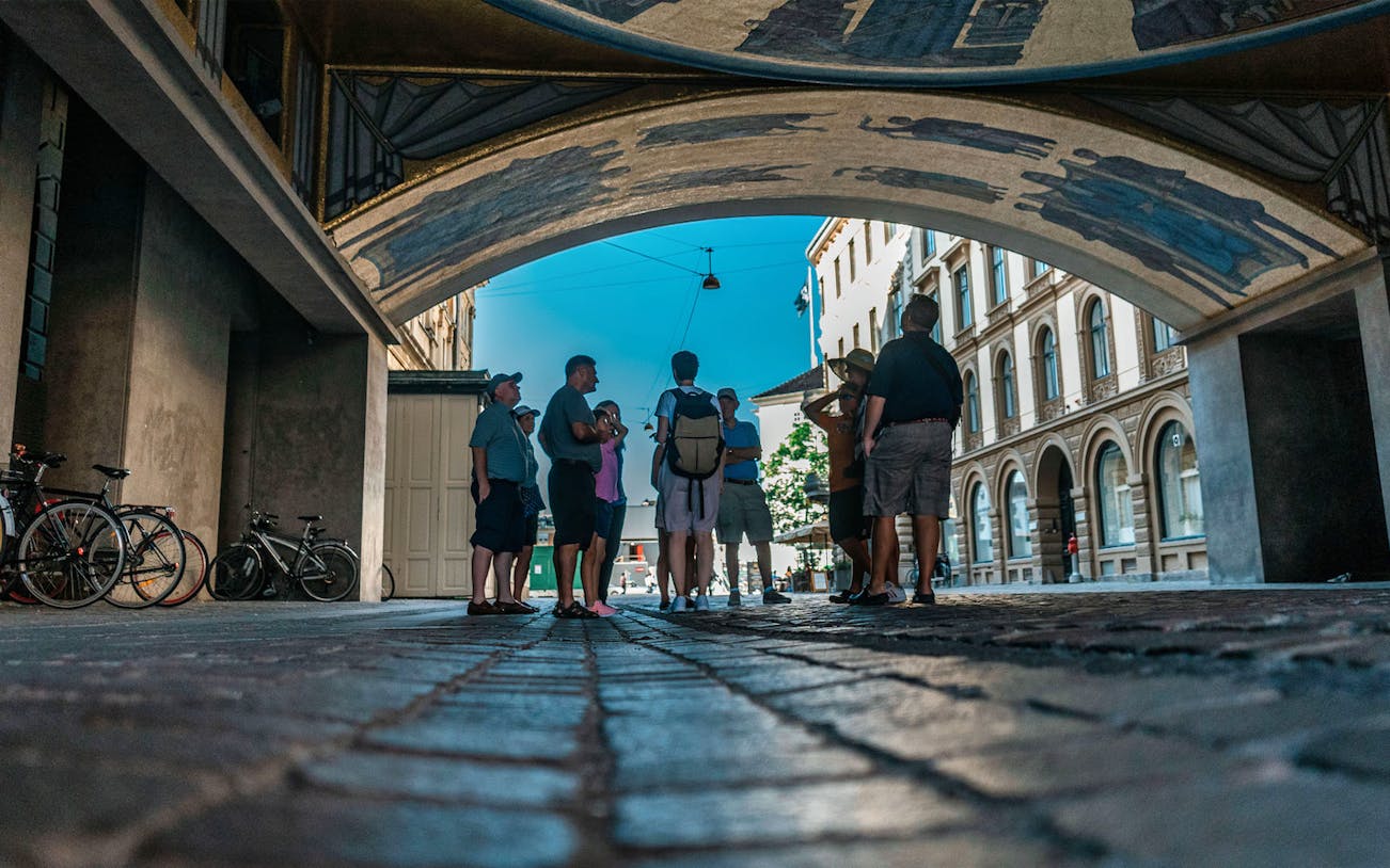 Group of tourists under an archway in Copenhagen on a walking tour near Christiansborg Palace.