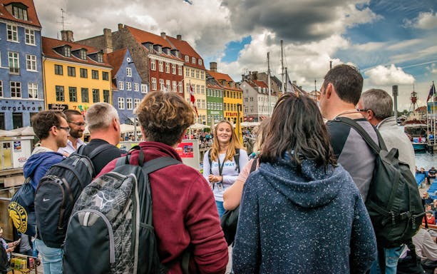 Tour group in Nyhavn, Copenhagen, with colorful buildings and canal in background.