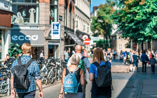 Tourists walking on a busy street in Copenhagen, Denmark, with shops and bicycles.