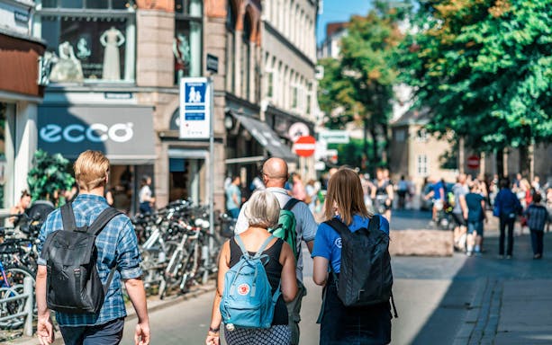 Tourists walking on a busy street in Copenhagen, Denmark, with shops and bicycles.