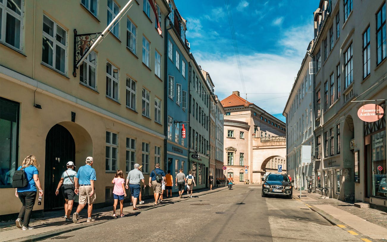 Group walking through Copenhagen Old Town street with historic buildings.