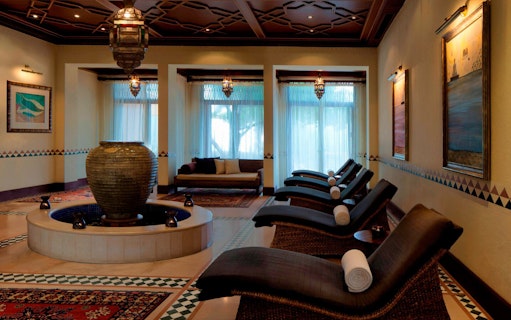 Luxurious spa lounge with reclining chairs and a central fountain at Al Maha Desert Resort & Spa Dubai.