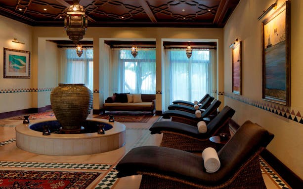 Luxurious spa lounge with reclining chairs and a central fountain at Al Maha Desert Resort & Spa Dubai.