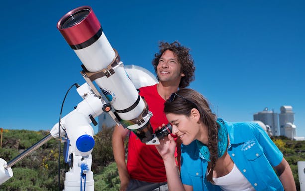 Visitors using a telescope at Teide Observatory during an astronomic tour in Tenerife.