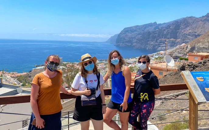 Tourists with masks enjoying the view of Los Gigantes cliffs and ocean in Tenerife.
