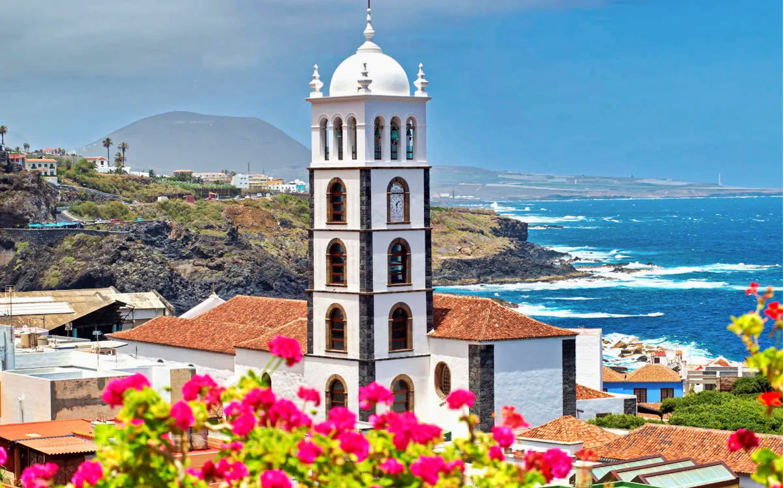 Church tower in Garachico with ocean and volcanic landscape in the background, Tenerife tour.