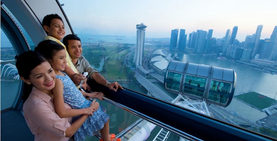 Family enjoying the view from Singapore Flyer with Marina Bay Sands in the background.