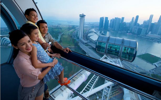 Family enjoying the view from Singapore Flyer with Marina Bay Sands in the background.