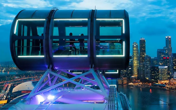 Singapore Flyer capsule overlooking Marina Bay Sands and city skyline at dusk.