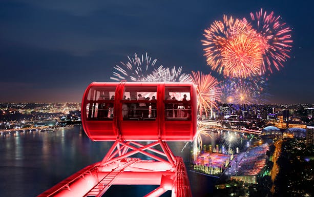 Singapore Flyer capsule with fireworks over Marina Bay at night.