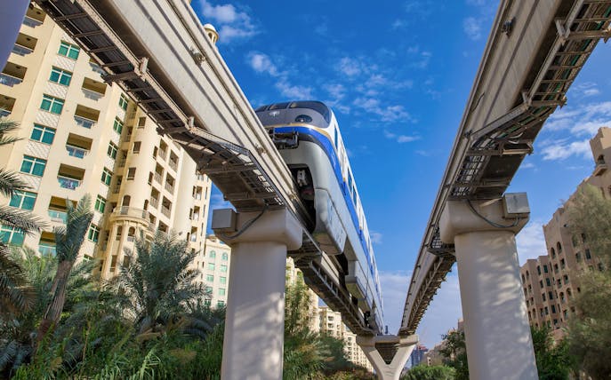 Palm Monorail traveling towards Nakheel Mall, Dubai, with residential buildings in the background.