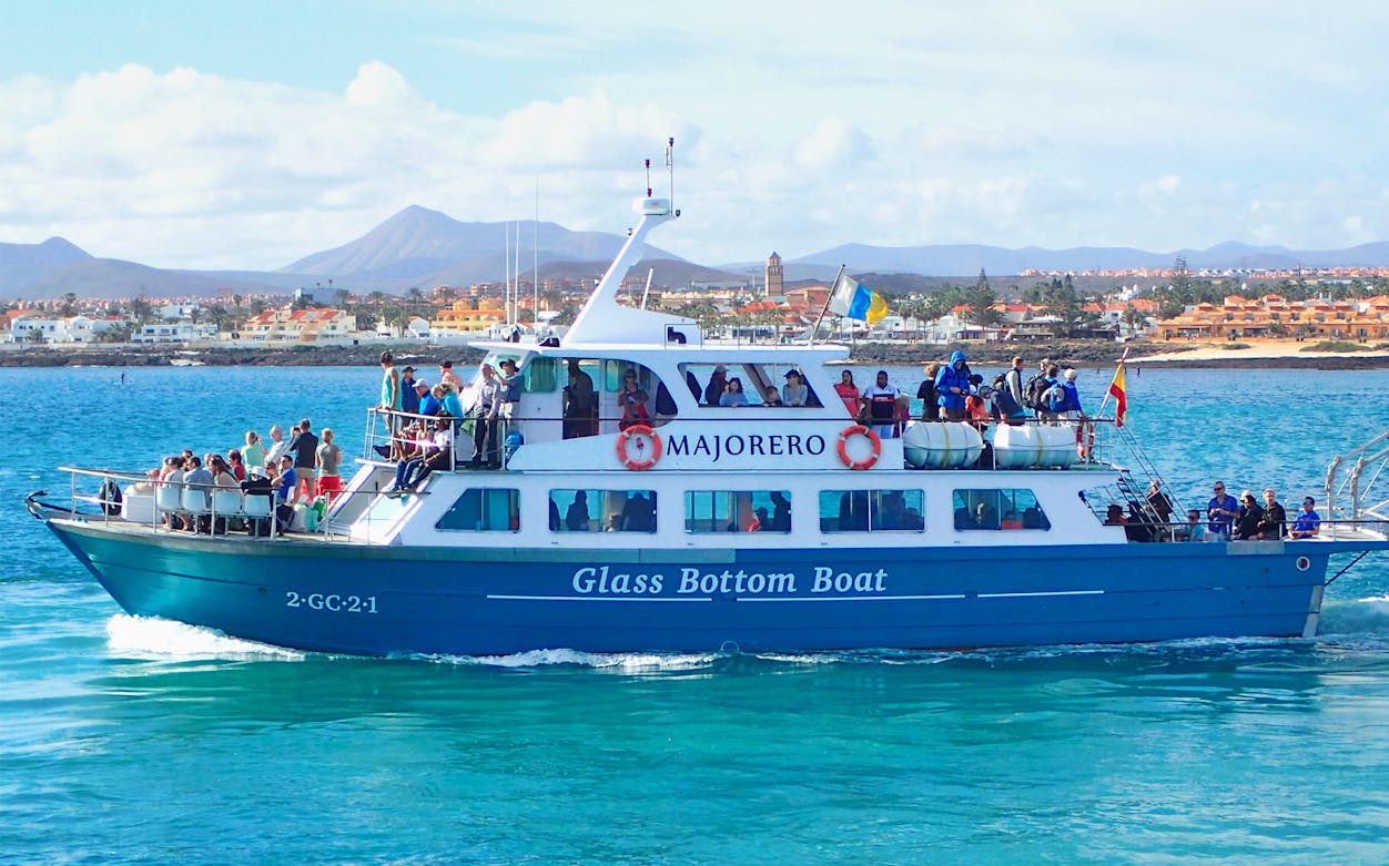 Ferry Lobos Express with passengers on a glass-bottom boat near coastal town.