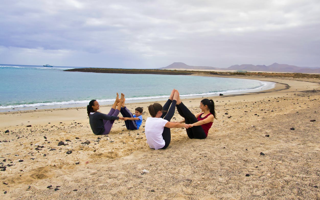 Group practicing yoga on Lobos Island beach, Corralejo, with ocean view.