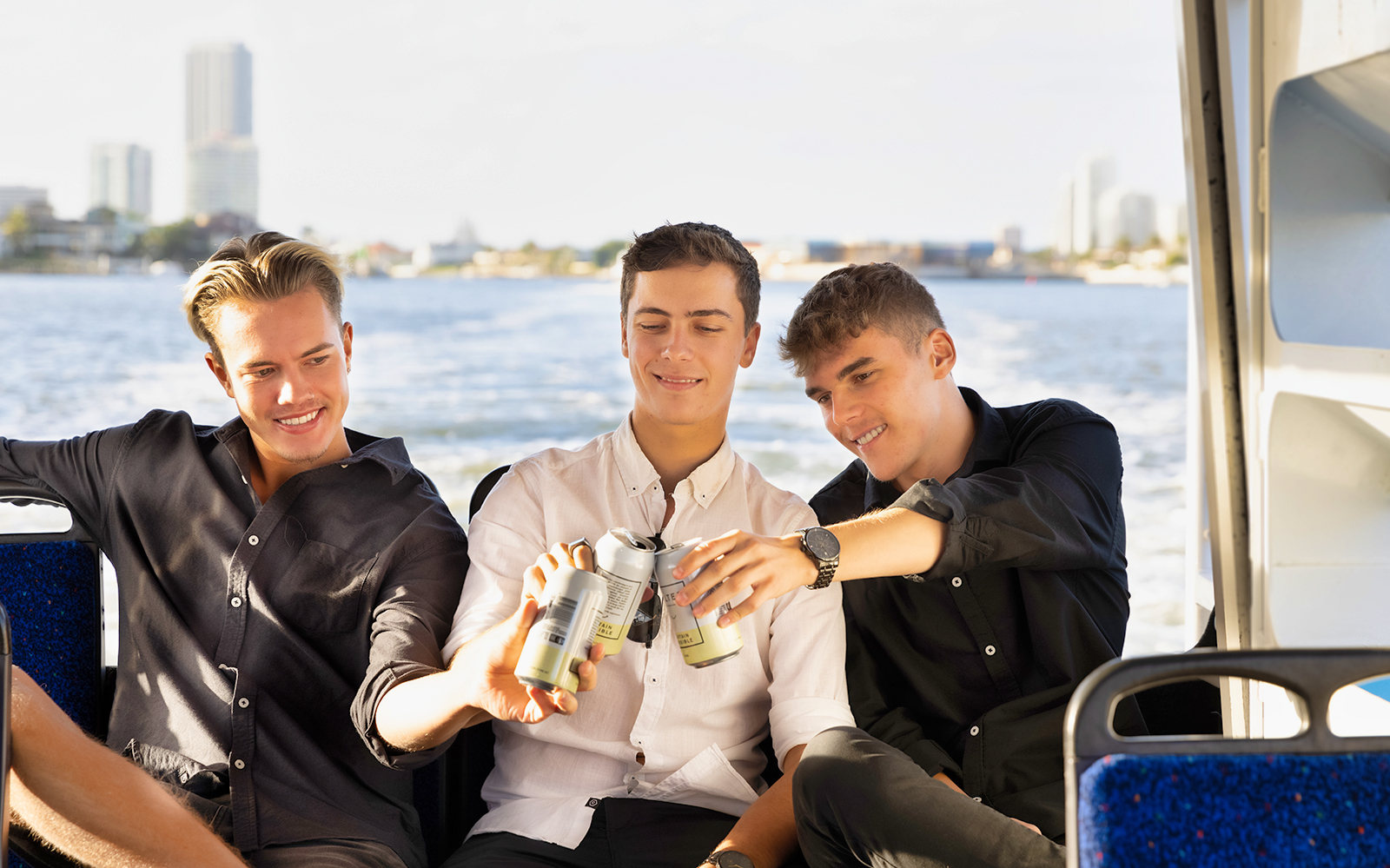 Three people enjoying drinks on the Aquaduck Gold Coast tour with city skyline in the background.