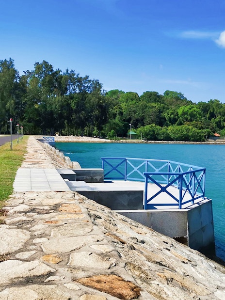 Pathway along the waterfront on Kusu Island, Singapore, with lush greenery in the background.