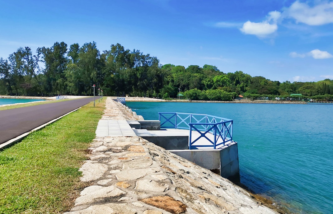 Pathway along the waterfront on Kusu Island, Singapore, with lush greenery in the background.