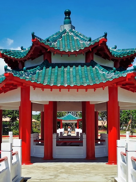 Pagoda on Kusu Island, Singapore, with red pillars and green tiled roof.