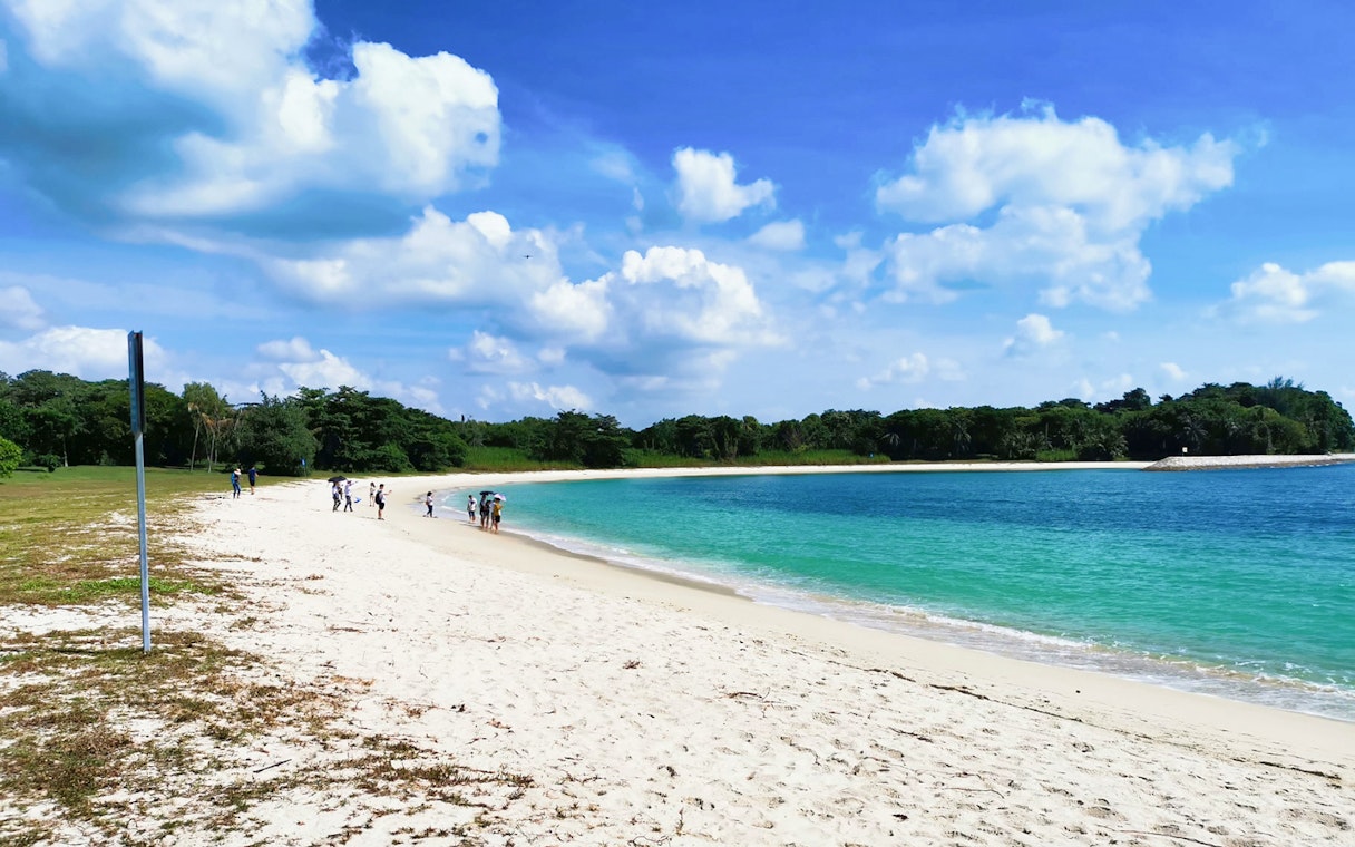 Visitors walking along the sandy beach on St John's Island, Singapore.