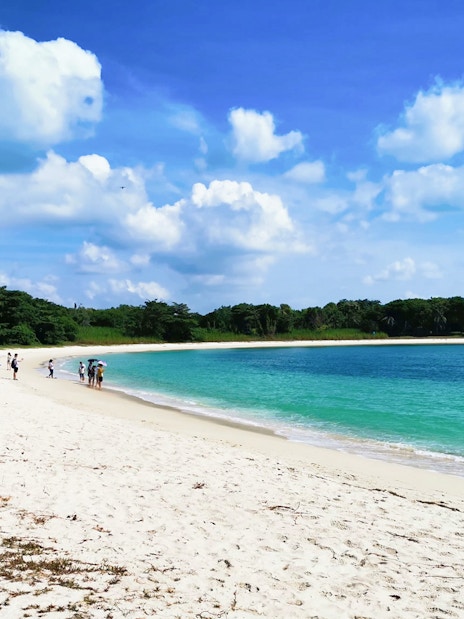 Visitors walking along the sandy beach on St John's Island, Singapore.