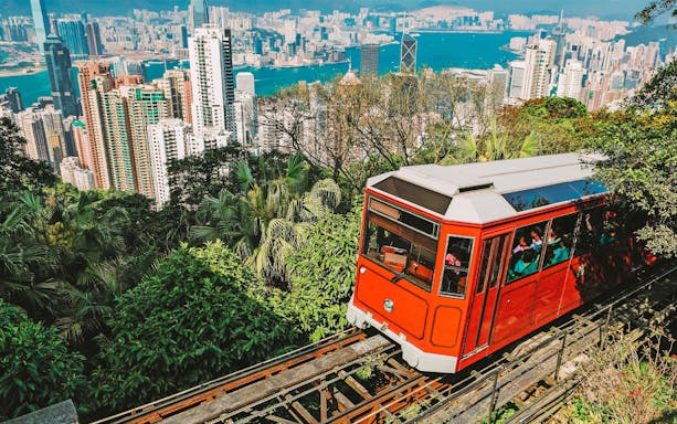 Tram ascending Victoria Peak with Hong Kong skyline in the background.