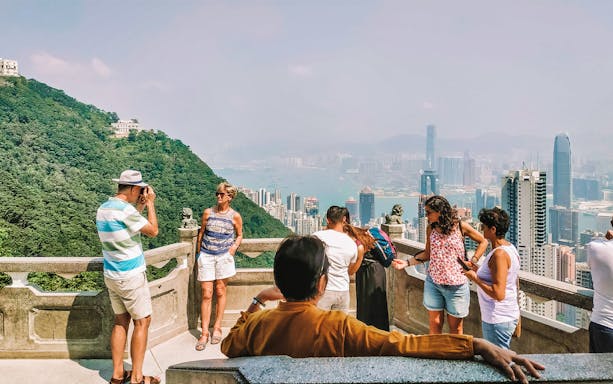 Group of tourists enjoying the view from Victoria Peak, Hong Kong during an evening hiking tour.