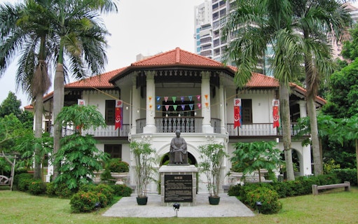 Sun Yat Sen Nanyang Memorial Hall with statue and flags in Singapore.