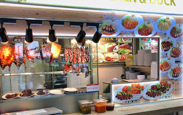 Food stall at Satay by the Bay, Singapore, displaying roasted meats and menu options.