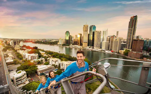Climbers ascending Brisbane's Story Bridge with city skyline and river view.